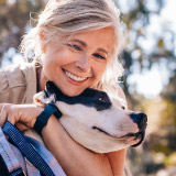 Older woman hugging her dog outside.