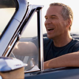 Older man smiling in a nice car. 