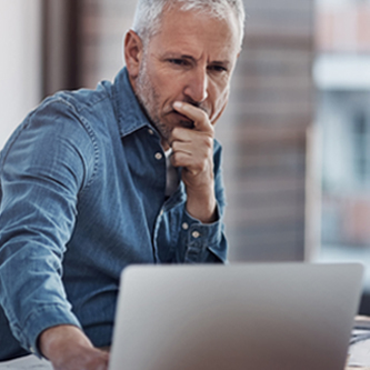 Older man looking sternly at a laptop. 