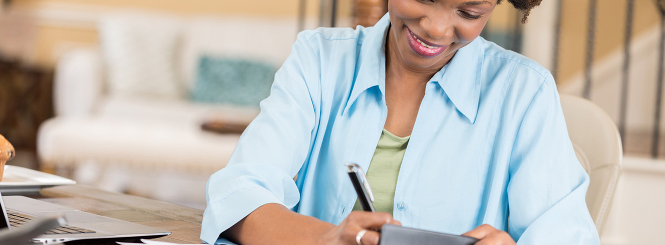 Woman writing a check at a table.