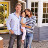 Young family posing together outside of a home. 