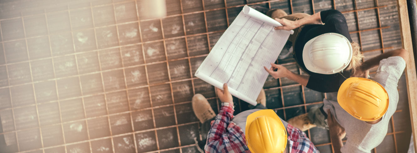 Top-down view of construction workers looking over a blueprint.