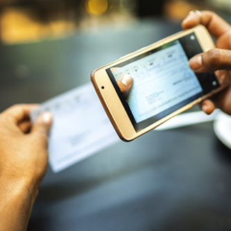 Close up of someone's hands taking a picture of a check with their phone. 