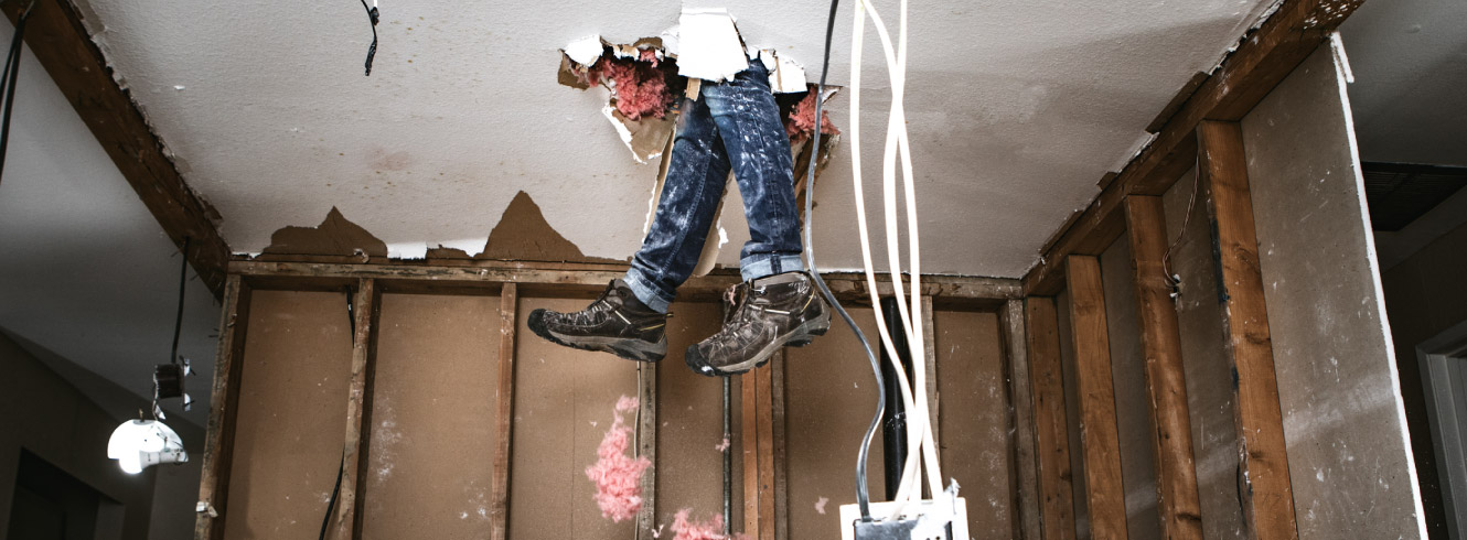 A person's feet are dangling from a hole in the ceiling.