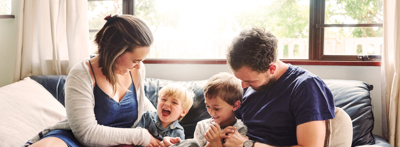 Young family playing and laughing on a couch.